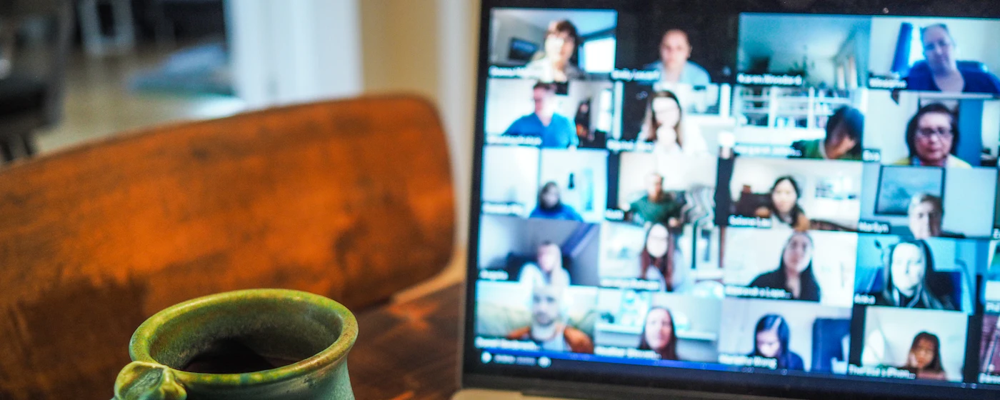 Ordinateur portable ouvert sur un appel visio, une tasse de café à côté